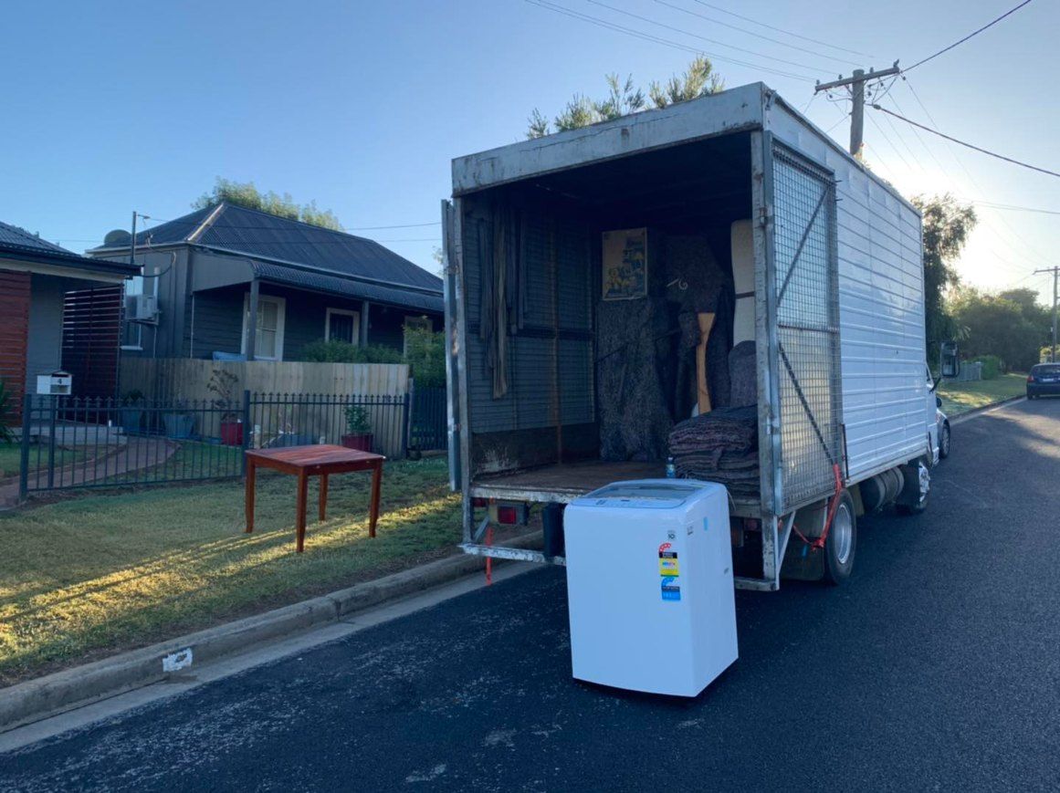 A Moving Truck is Parked on the Side of the Road Next to a House — Buck Removals & Storage in Cowra, NSW