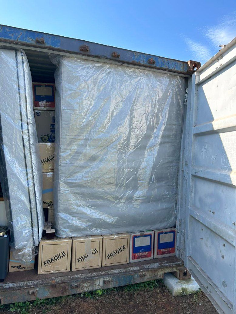 A Shipping Container Filled With Boxes and a Tarp — Buck Removals & Storage in Orange, NSW