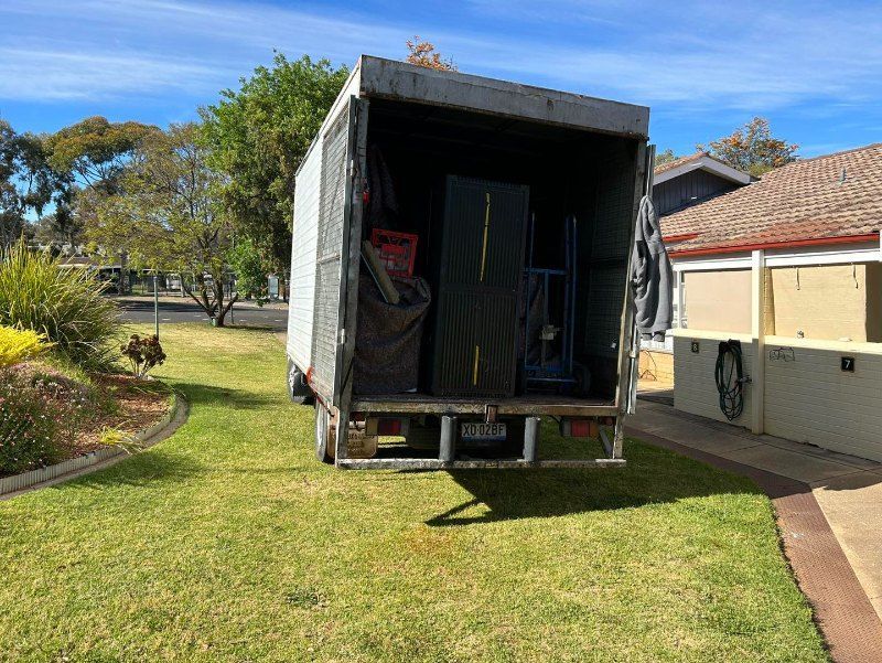 A Moving Truck is Parked in the Grass in Front of a House — Buck Removals & Storage in Cowra, NSW