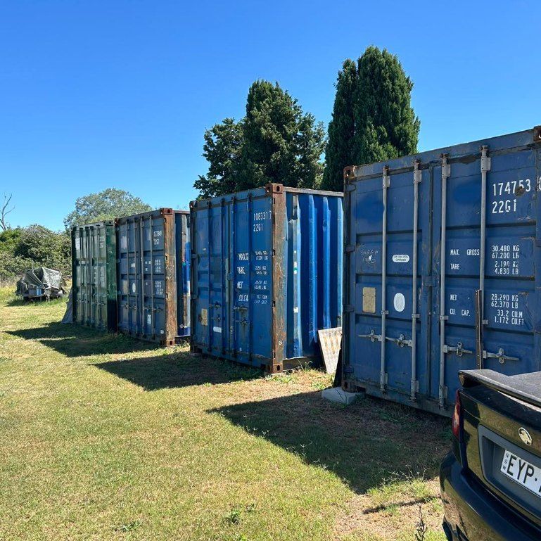 A Row of Blue Shipping Containers Are Lined Up in a Grassy Field — Buck Removals & Storage in Cowra, NSW