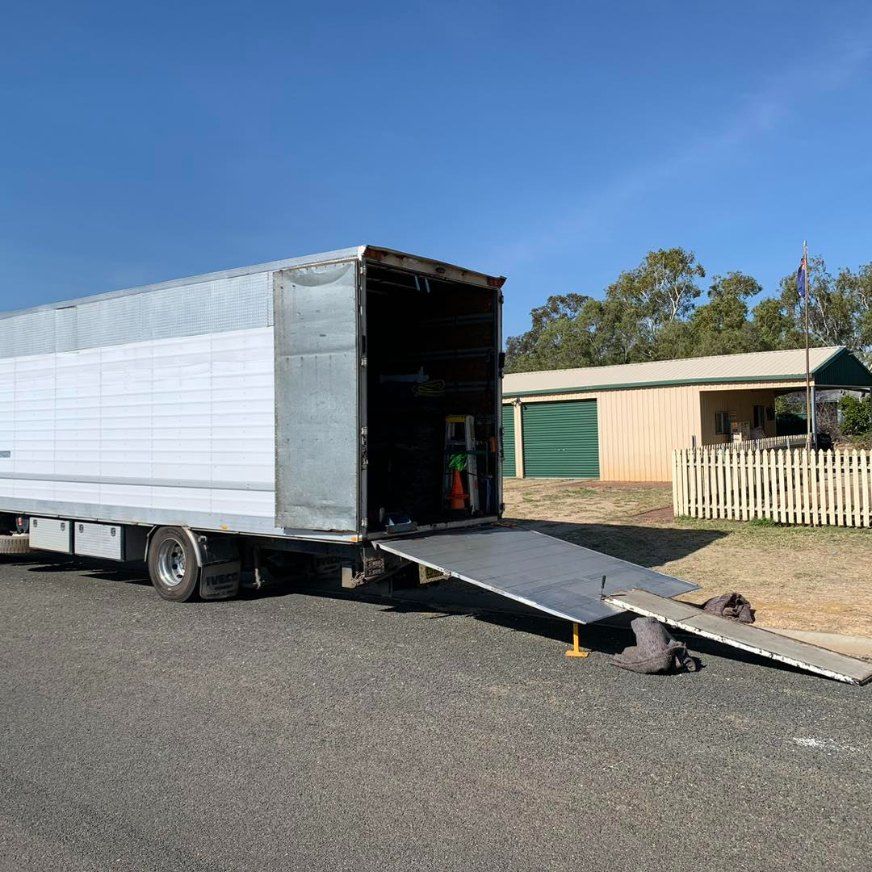 A Moving Truck With a Ramp Attached to It is Parked in Front of a House — Buck Removals & Storage in Bathurst, NSW