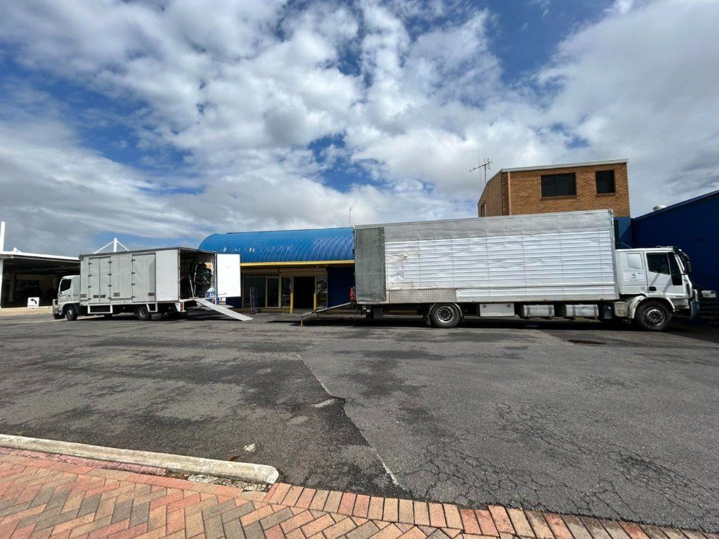 Two Trucks Are Parked in a Parking Lot in Front of a Building — Buck Removals & Storage in Dubbo, NSW