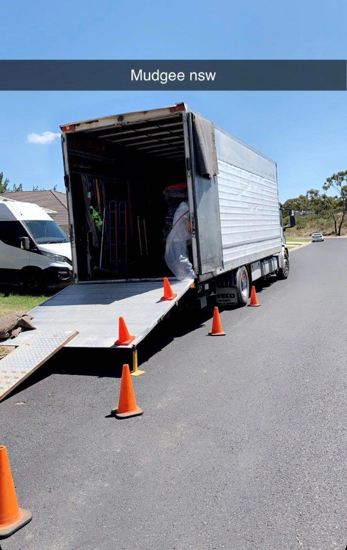 A Man is Loading a Truck With a Ramp on the Side of the Road — Buck Removals & Storage in Parkes, NSW
