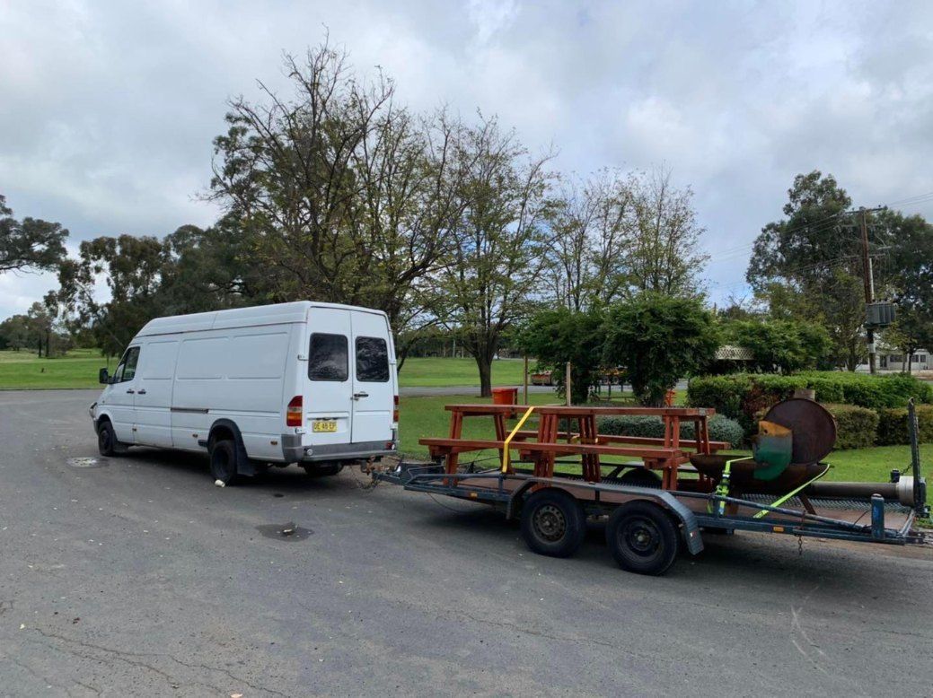 A White Van is Towing a Trailer With a Picnic Table on It — Buck Removals & Storage in Forbes, NSW
