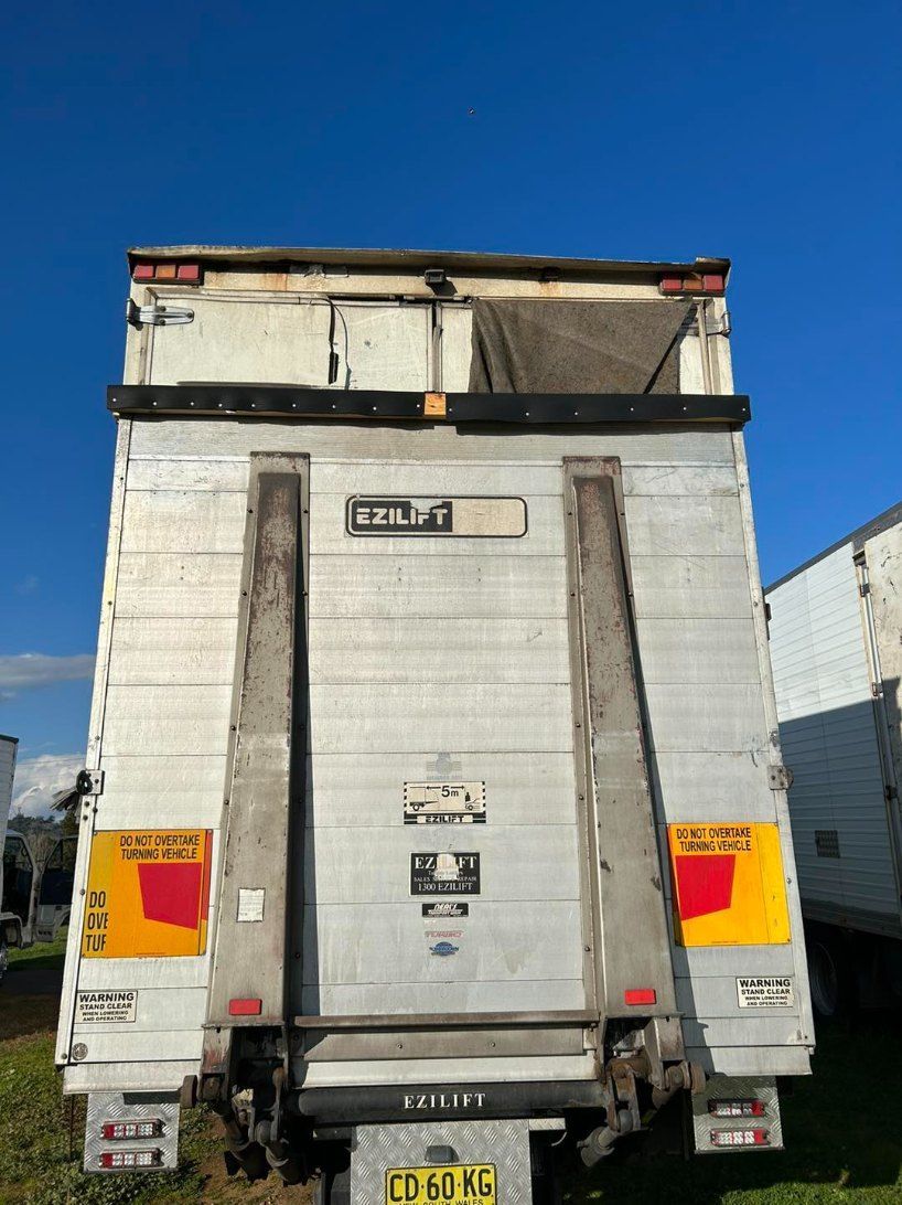 The Back of a Truck With a Lift on It is Parked in a Field — Buck Removals & Storage in Cowra, NSW