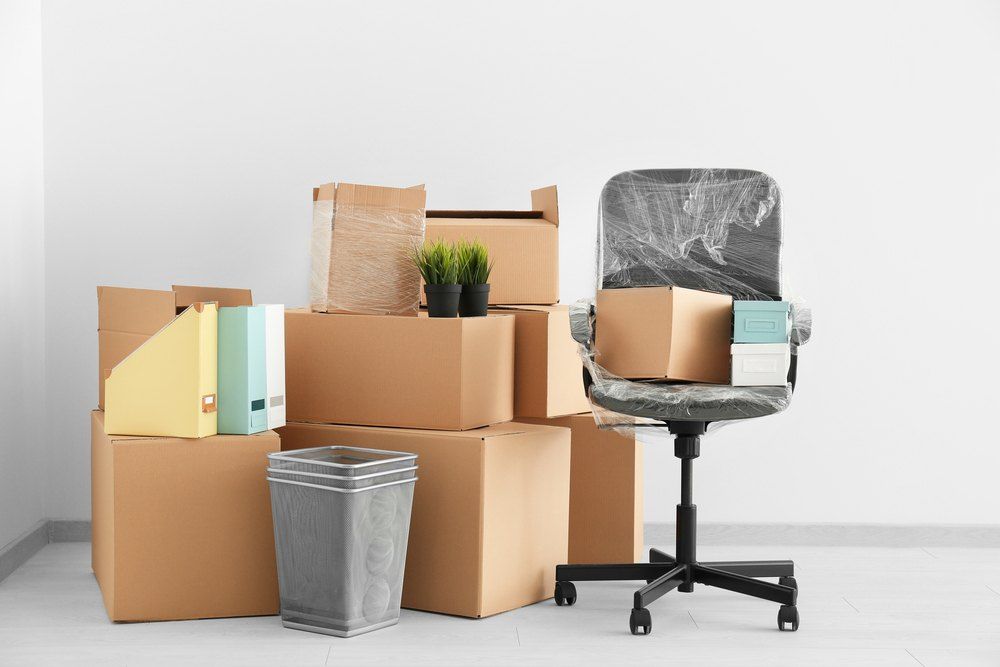 A Chair is Sitting Next to a Pile of Cardboard Boxes — Buck Removals & Storage in Orange, NSW
