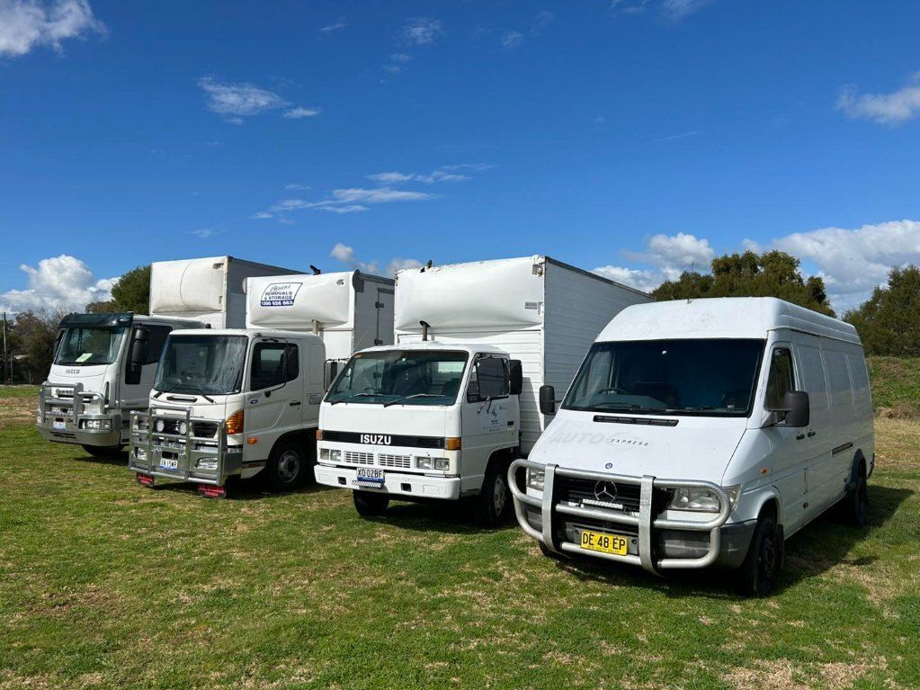 A Row of Moving Trucks Are Parked in a Grassy Field — Buck Removals & Storage in Cowra, NSW