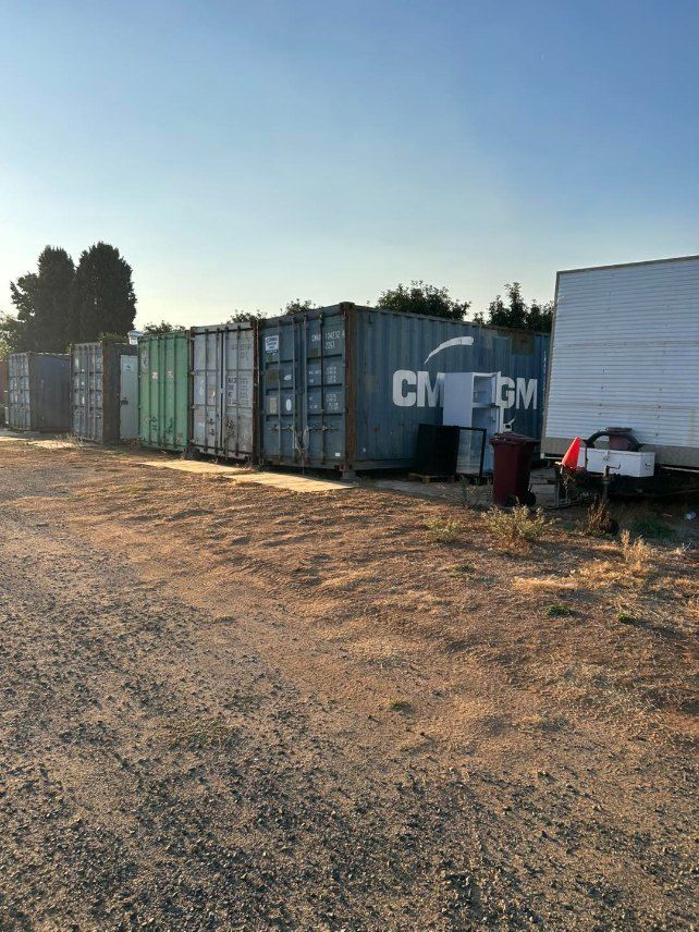 A Row of Shipping Containers Are Lined Up in a Dirt Field — Buck Removals & Storage in Cowra, NSW