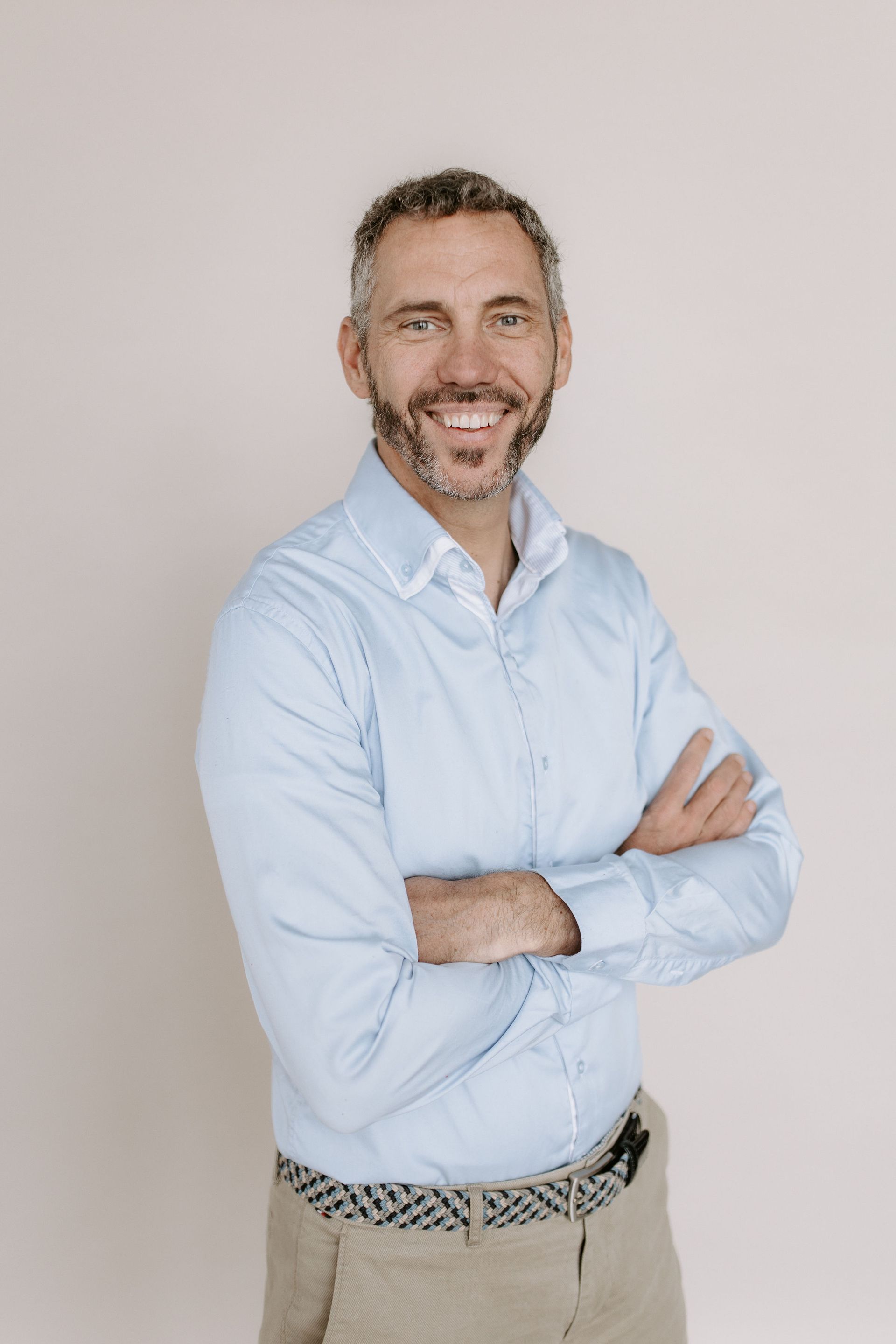 Ein Mann mit Bart steht mit verschränkten Armen da und lächelt.