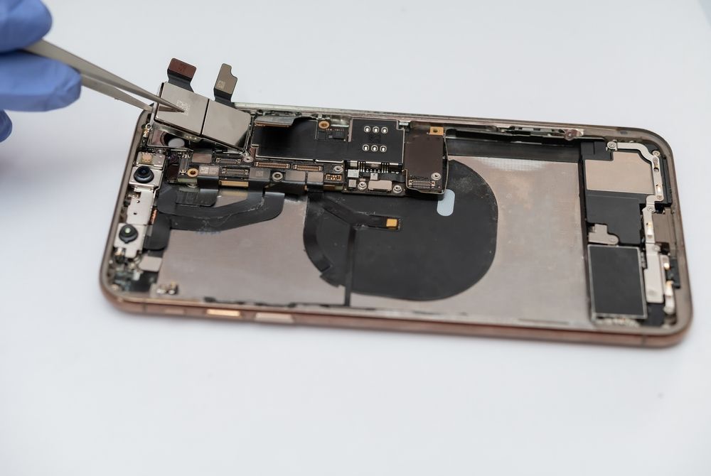 Person in Blue Gloves Using Tweezers to Remove Part of a Disassembled Cell Phone — Phone Hut in Alice Springs, NT
