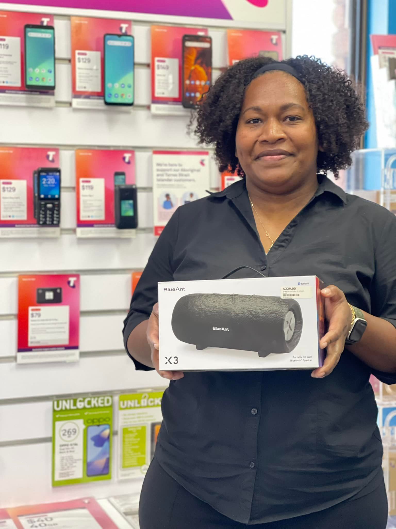 Woman Holding a Black Speaker in a T-mobile Store, Phones Displayed Behind Her — Phone Hut in Alice Springs, NT