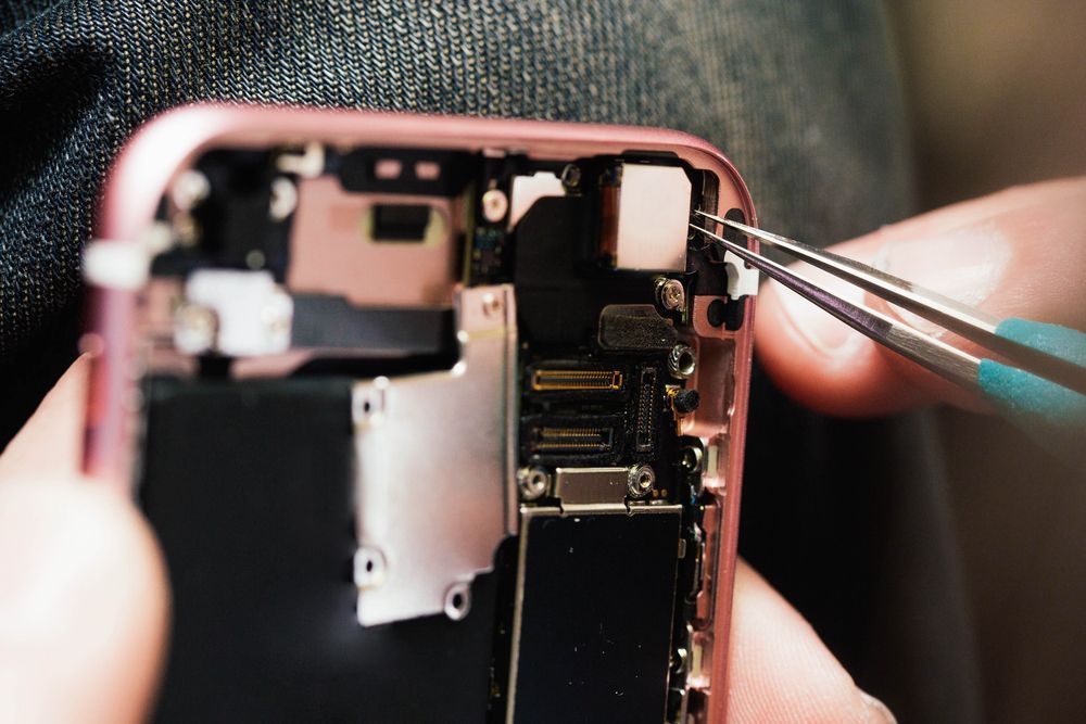 Person Using Tweezers to Repair a Disassembled Rose Gold Smartphone — Phone Hut in Alice Springs, NT