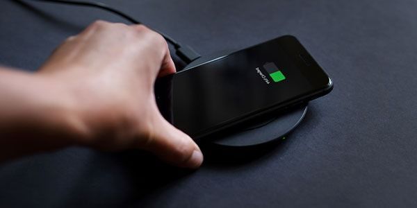 Hand Placing a Black Phone on a Wireless Charger — Phone Hut in Alice Springs, NT
