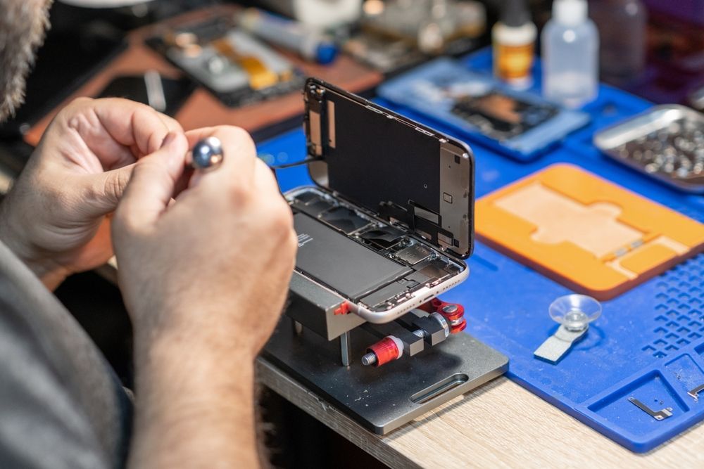Person Repairs a Smartphone, Using Tools on a Blue Mat — Phone Hut in Alice Springs, NT