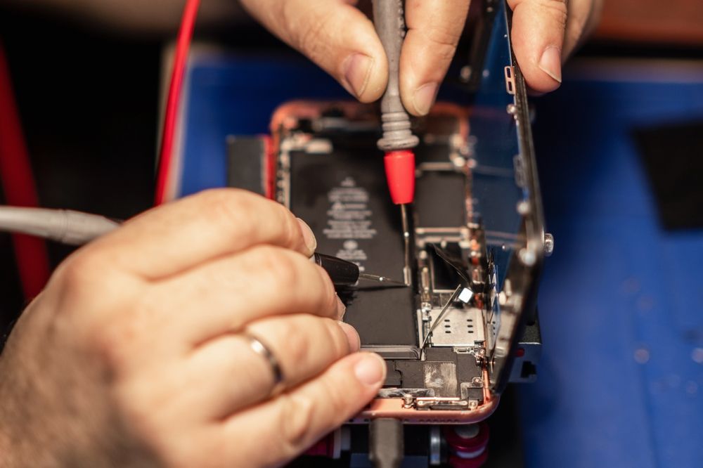 Hands Testing a Disassembled Phone's Circuit Board — Phone Hut in Alice Springs, NT