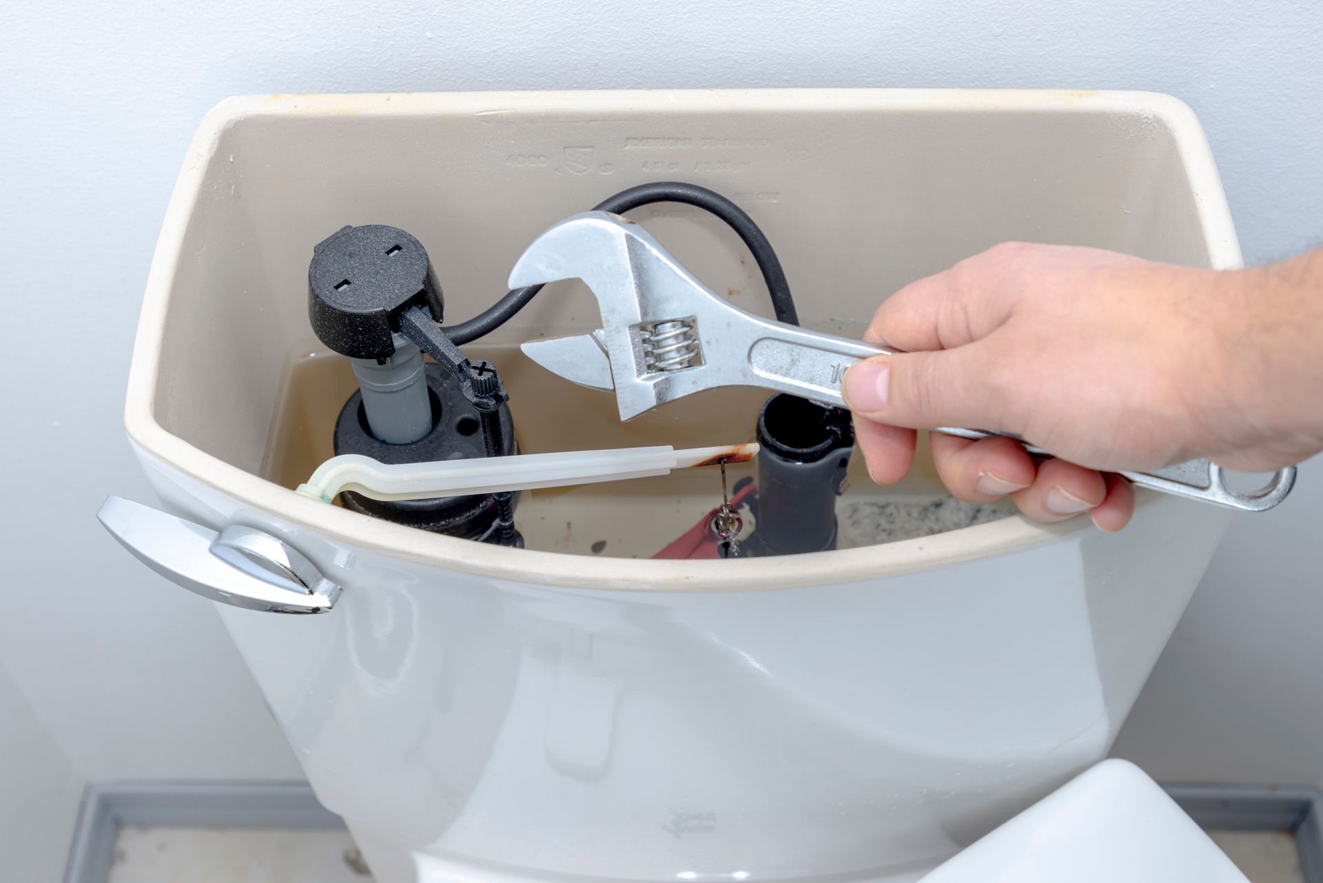 Hand tightening a toilet tank fill valve with an adjustable wrench