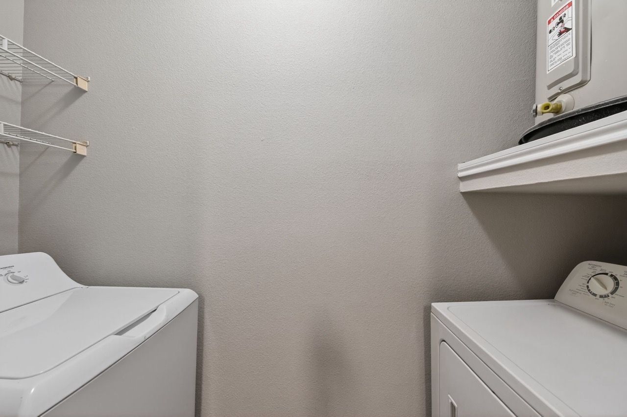 Compact laundry room with a washer and dryer and wire shelving.