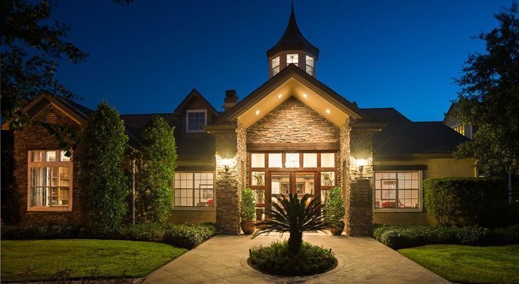Night exterior view of a modern apartment community entrance with stone columns.