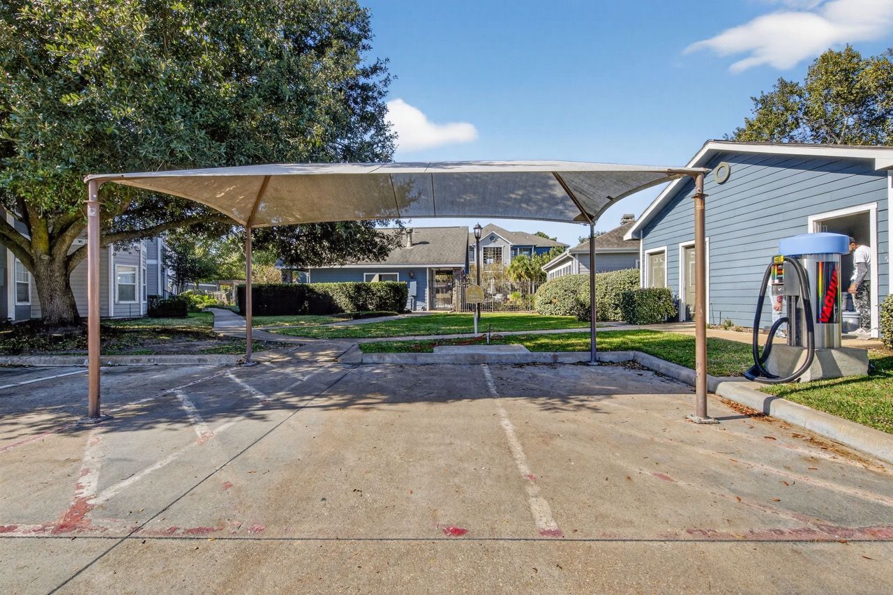 Shade canopy over parking stalls between blue apartment buildings.