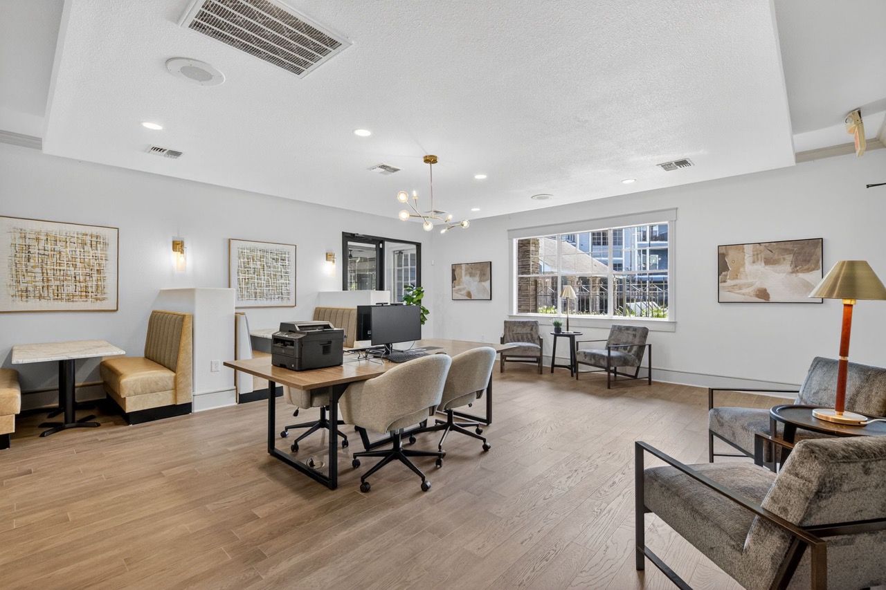Bright community lounge with desks, chairs, and a large window.