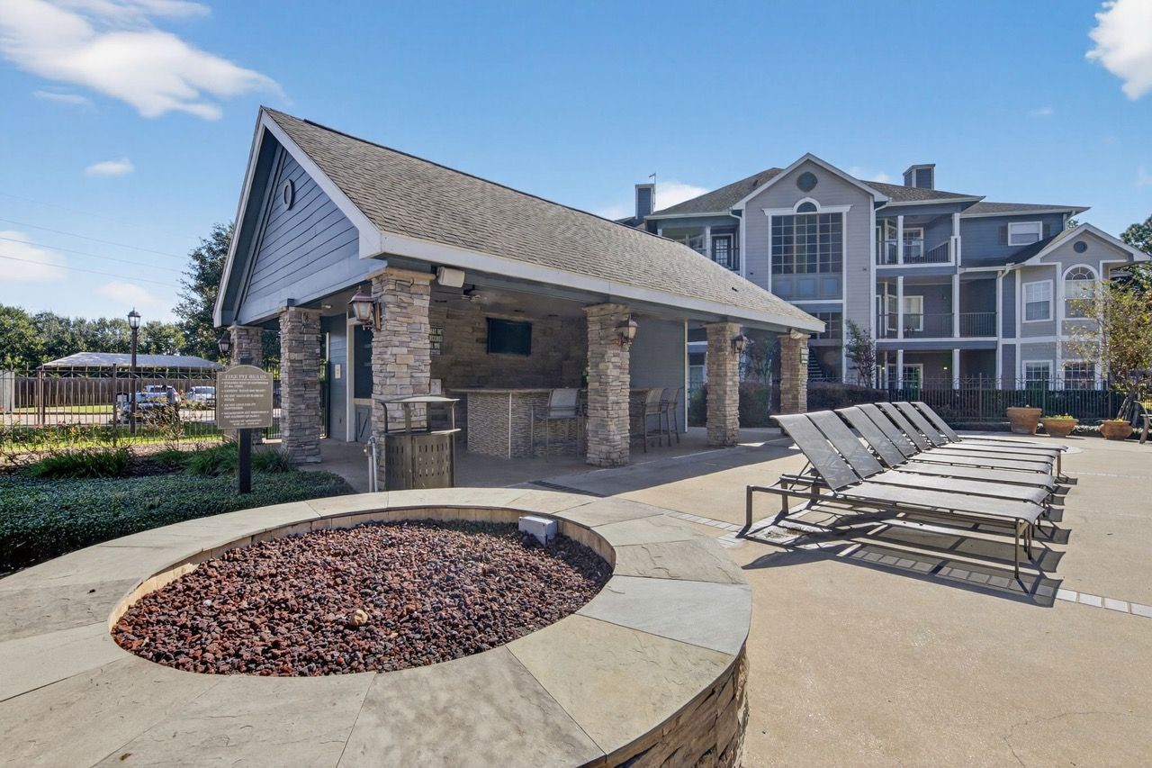 Outdoor poolside lounge with sun loungers and a covered pavilion at a multifamily community.