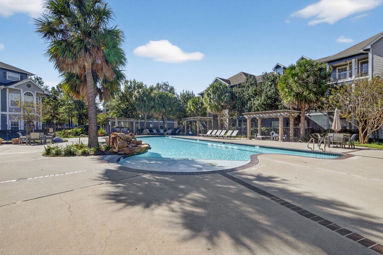 Outdoor community pool with lounge chairs and palm trees