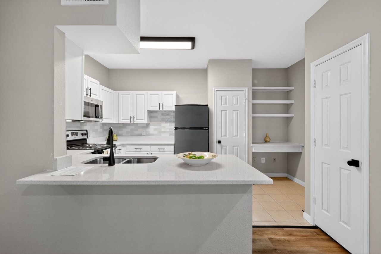 Open-concept kitchen with white cabinets, stainless steel appliances, and a large island.