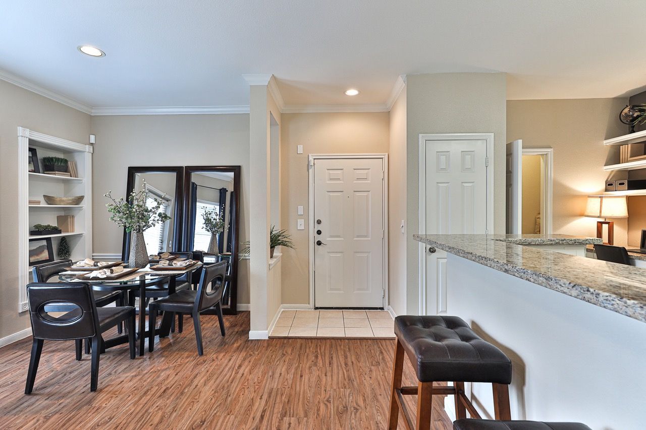 Open dining area with black dining table and chairs, mirrored wall, and granite kitchen counter.