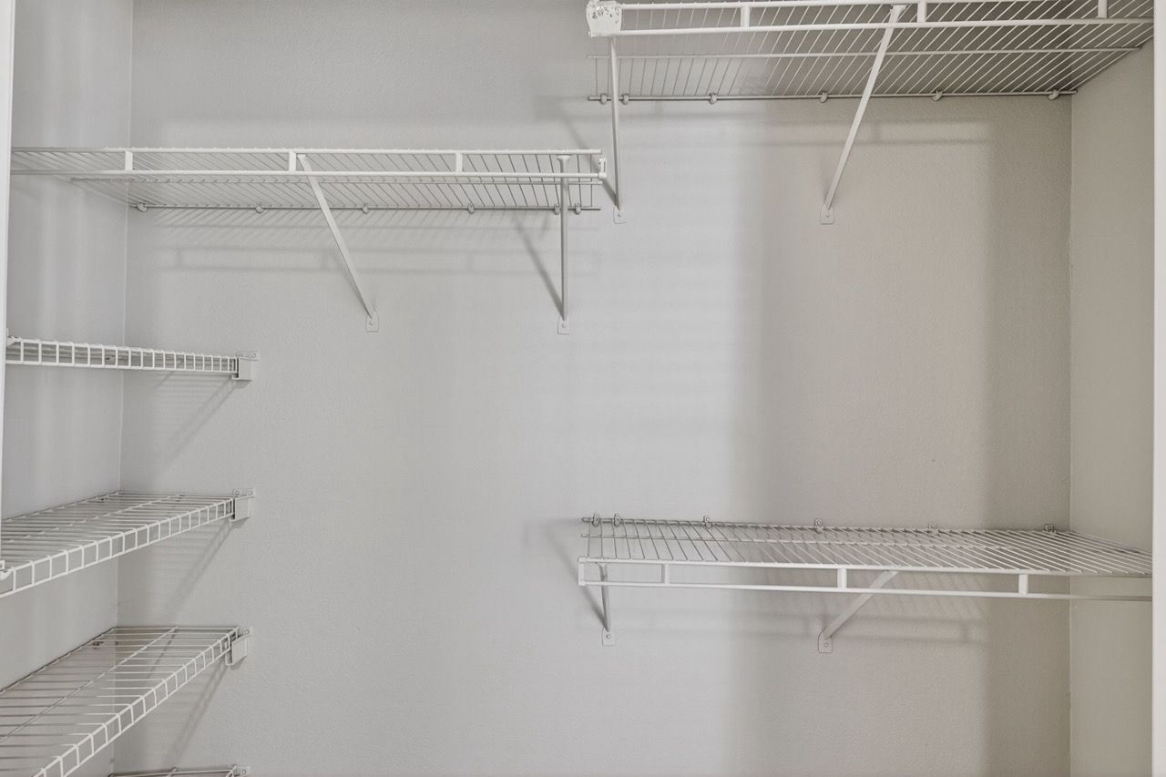 Empty white walk-in closet with metal wire shelves and rods.