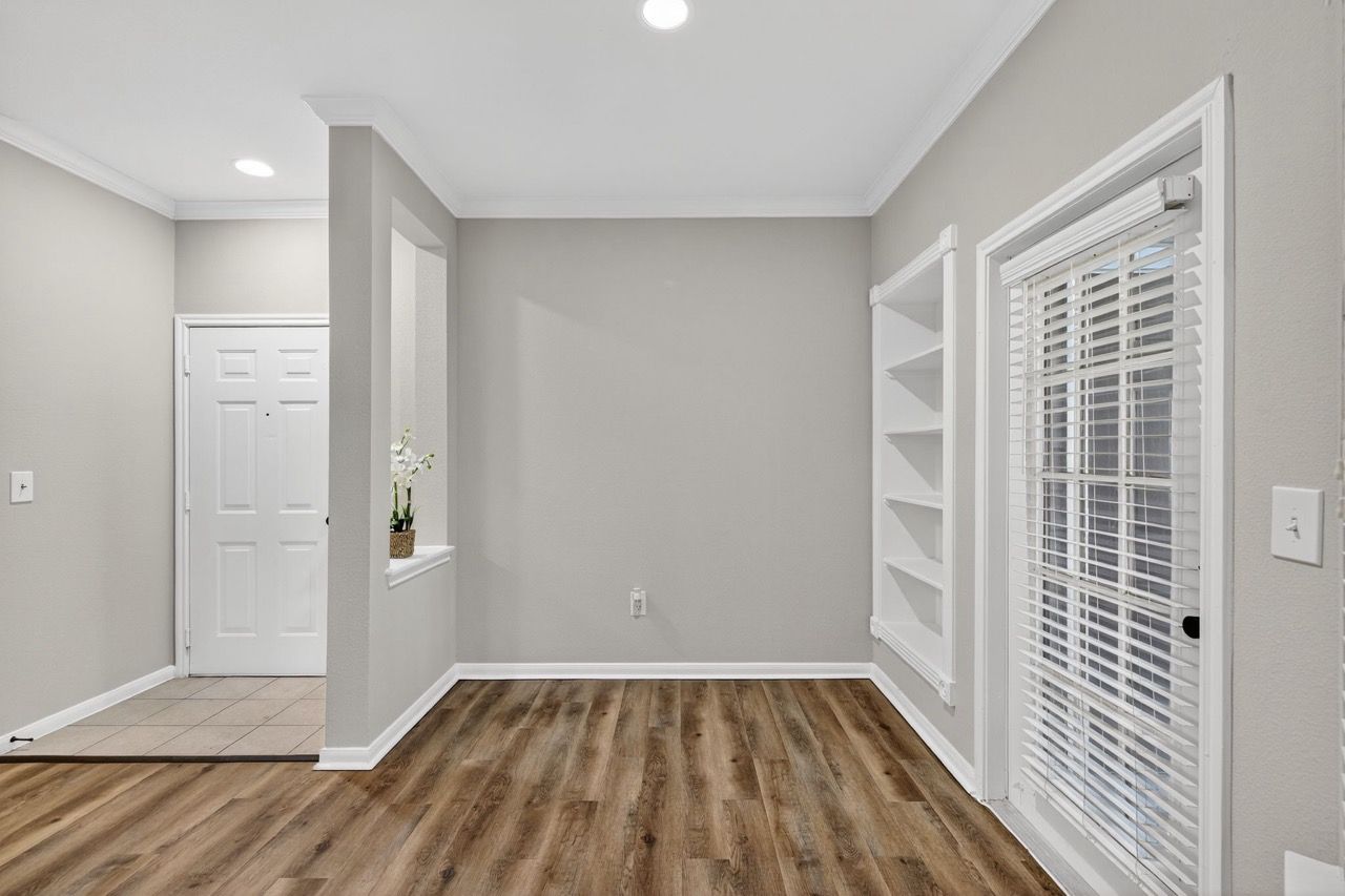 Interior living area with gray walls, white trim, built-in shelves, and a door with blinds.