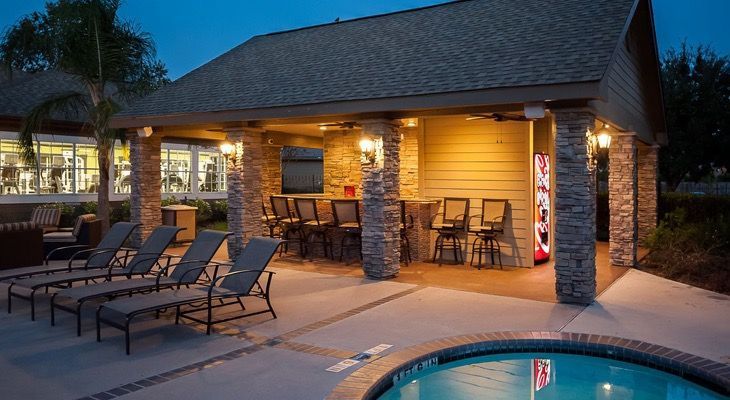 Outdoor pool area with lounge chairs and a covered seating bar pavilion.