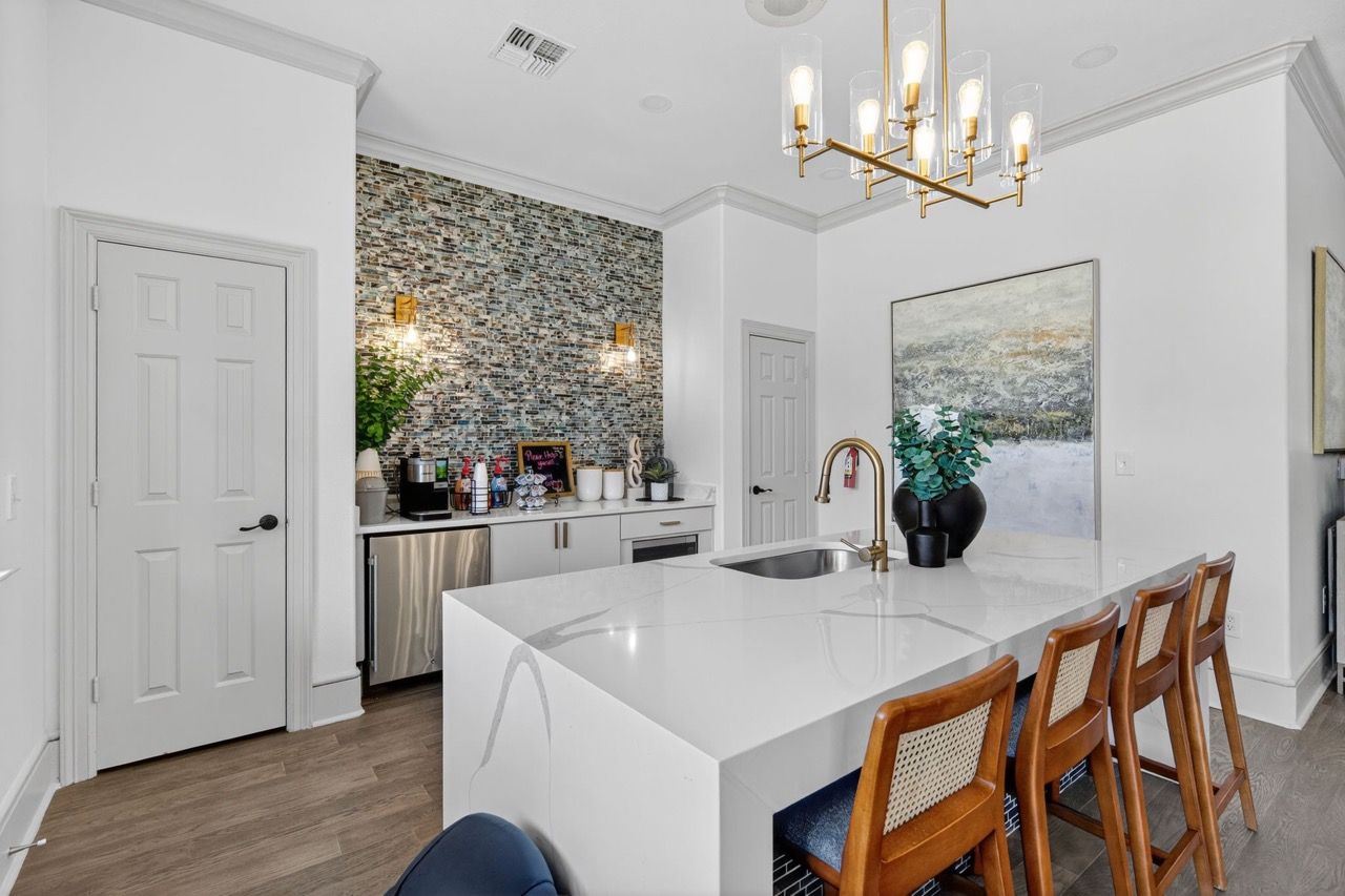 Modern kitchen with white island, mosaic tile backsplash, and wooden bar stools.