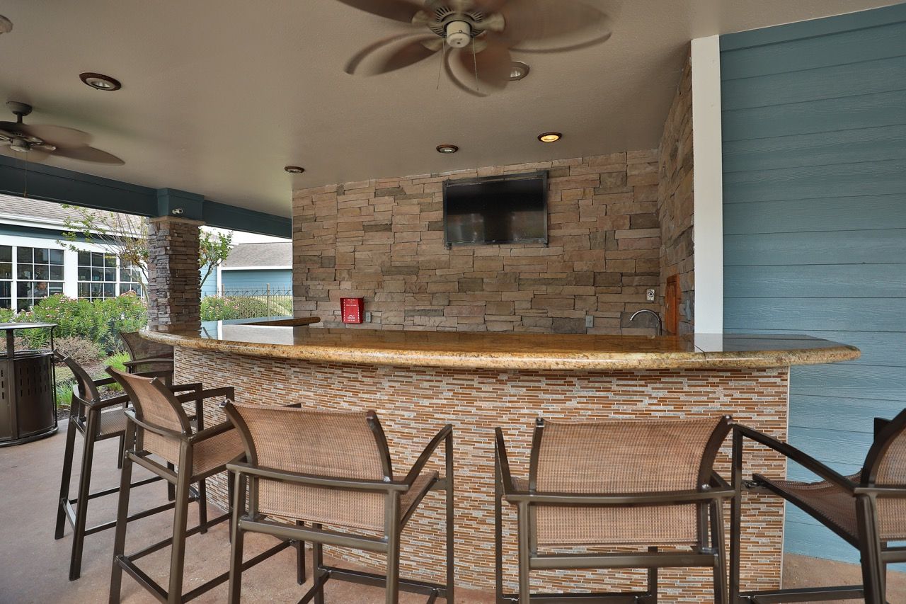 Outdoor communal bar area with stone wall, granite counter, and bar-height seating.