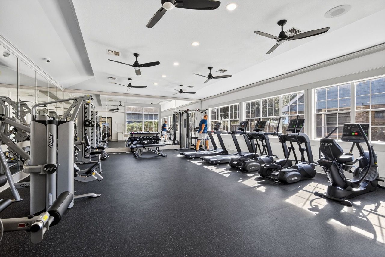 Bright gym interior with treadmills, ellipticals, and weight machines.
