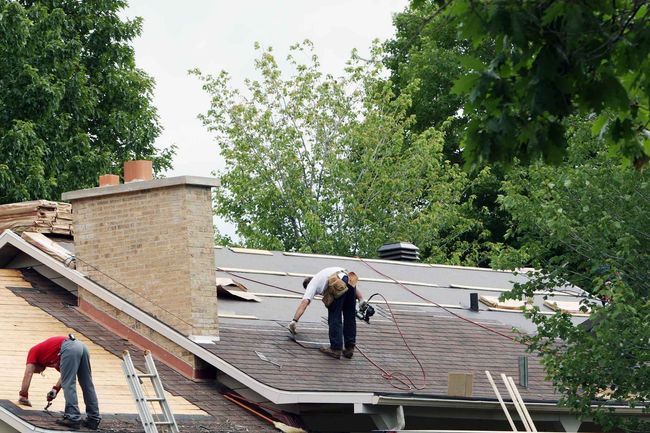 Two men are working on the roof of a house