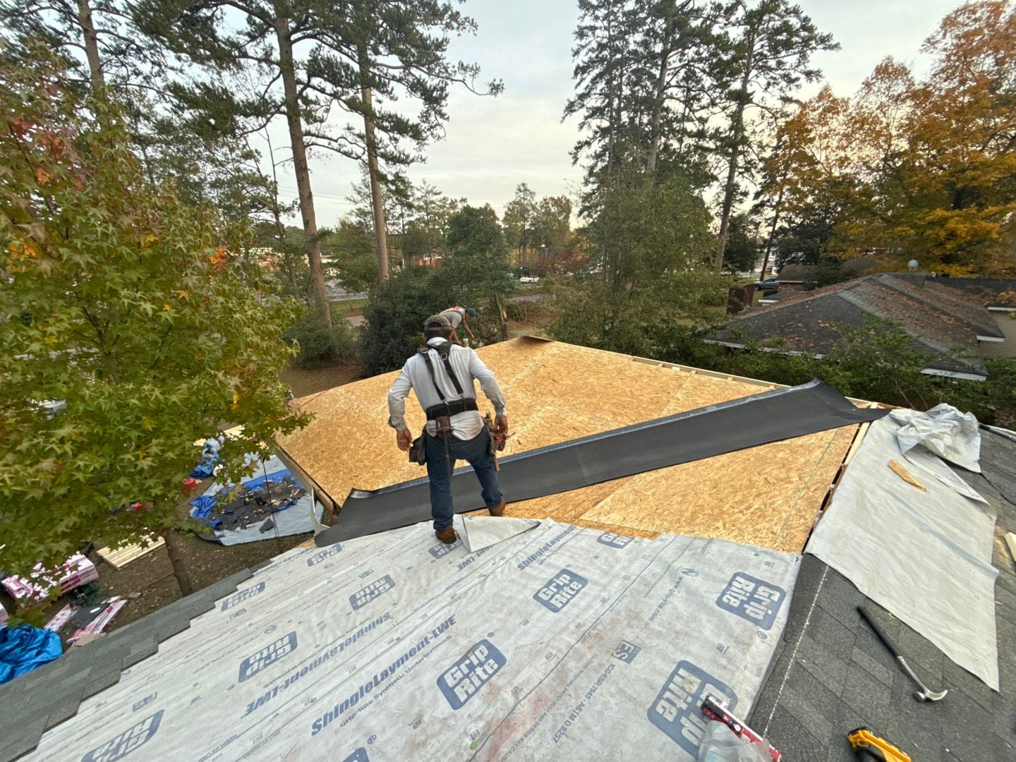 Two construction workers are working on the roof of a building.