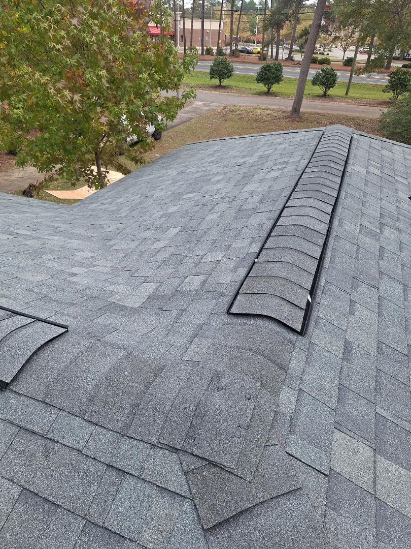 A construction worker is sitting on top of a metal roof.