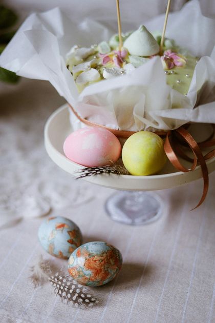 A white plate topped with easter eggs and candles on a table.