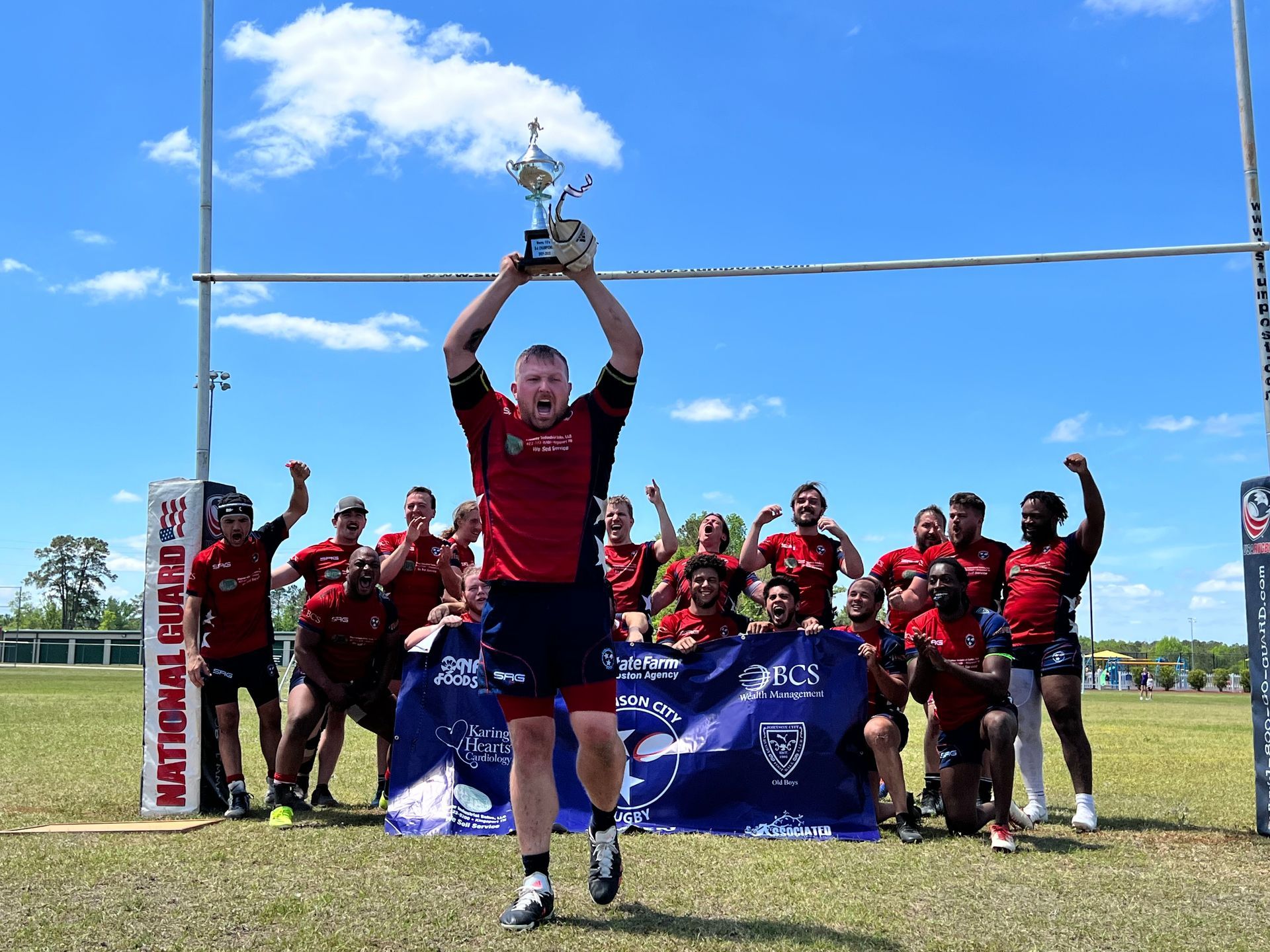 A man is holding up a trophy in front of a group of rugby players