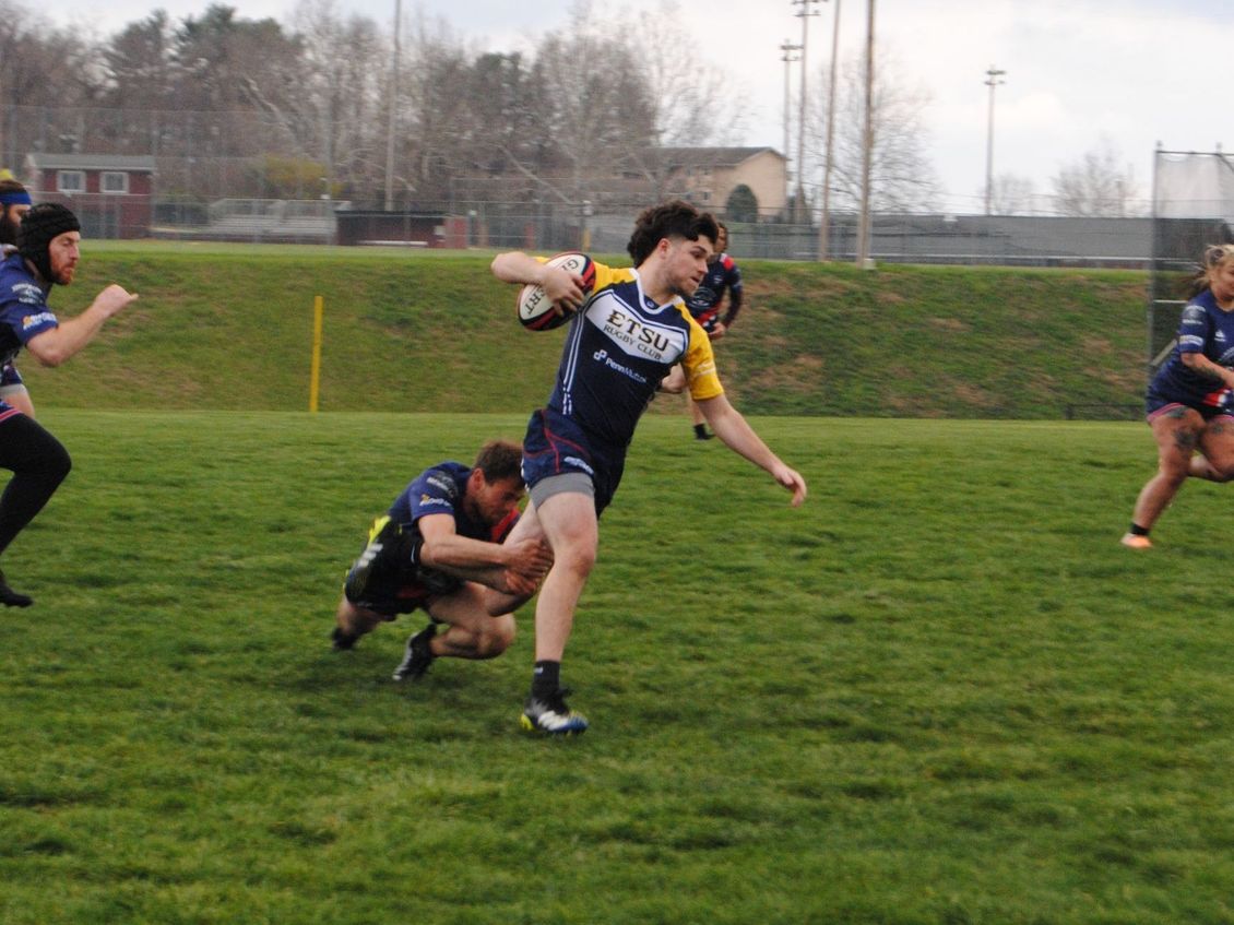 A group of people are playing a game of rugby on a field.