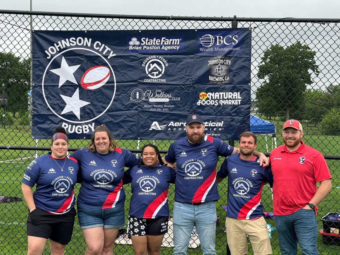 A group of people are posing for a picture in front of a johnson city rugby banner.