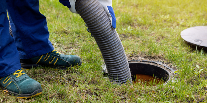 A person is pumping a hose into a septic tank.