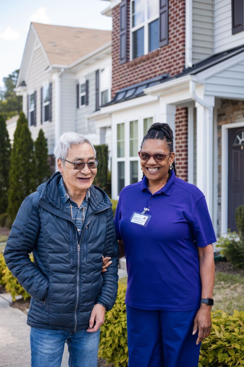 Nurse in scrubs reviews tablet with group of seniors in a living room; one uses wheelchair. Nurse in scrubs reviews tablet with group of seniors in a living room; one uses wheelchair.