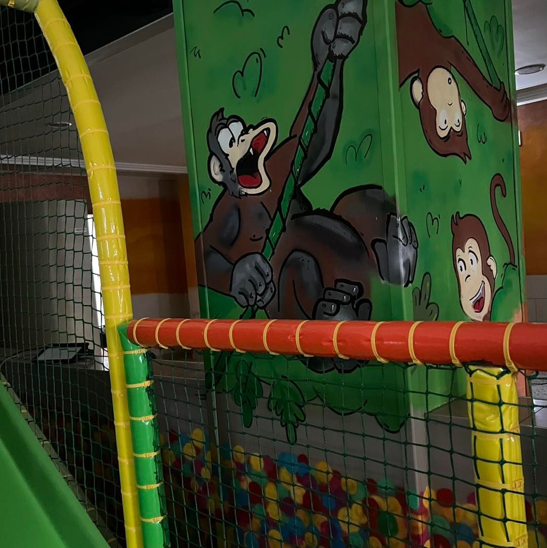 Parco giochi al coperto con murale raffigurante una scimmia e piscina di palline.
