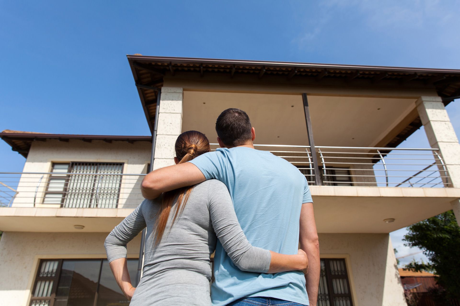 A man and a woman are standing in front of a house.
