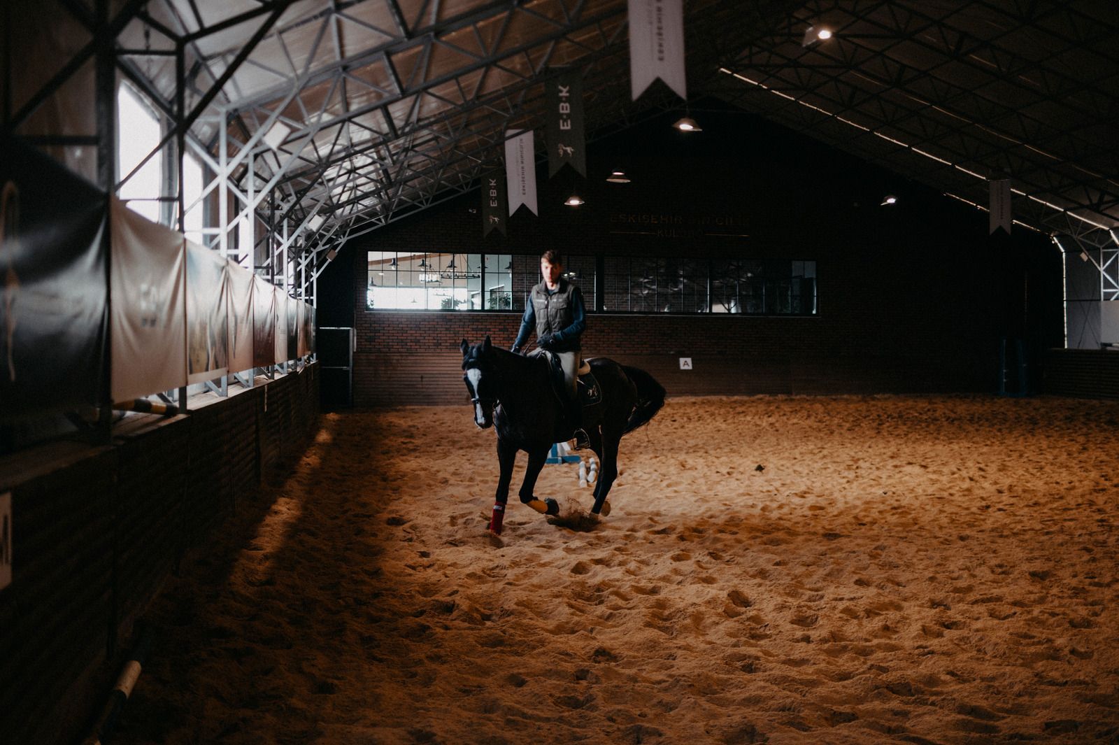 A man is riding a horse in an indoor arena.