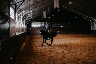 A man is riding a horse in an indoor arena.