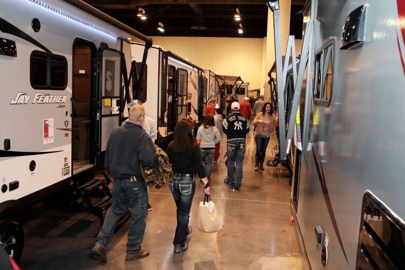 People walking through an RV show, viewing travel trailers.