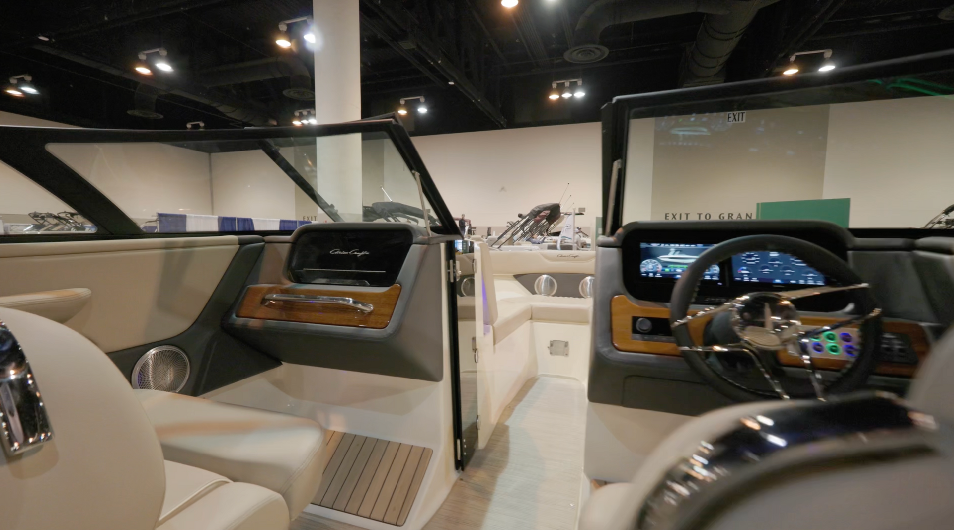 Interior of a boat cabin with wood trim, grey and white seats, and digital displays.