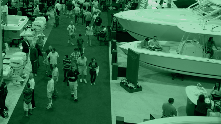Crowd walking through a boat show; various boats on display, mostly white.